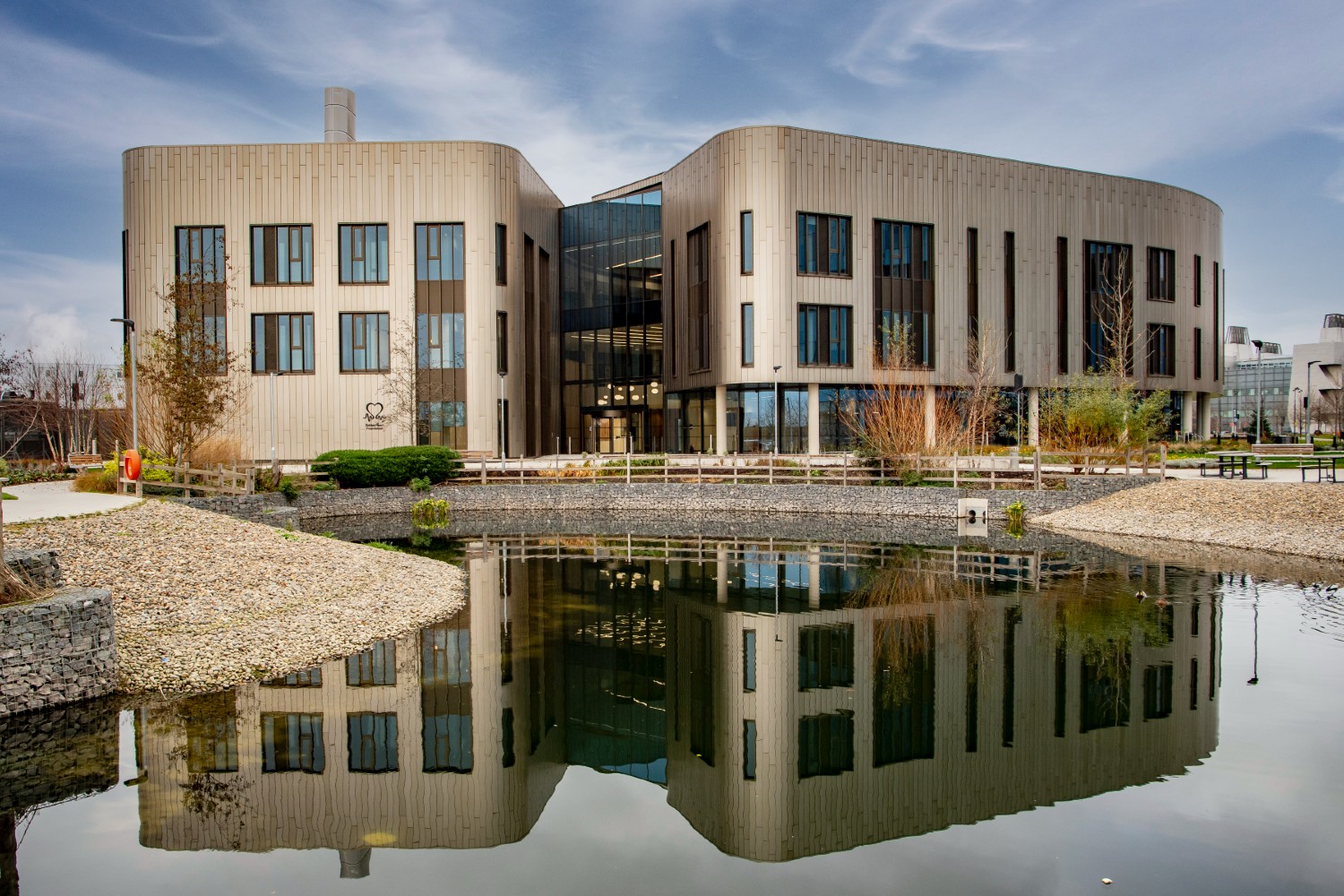 A building with windows and a glass frontage in the centre in front of a duck pond