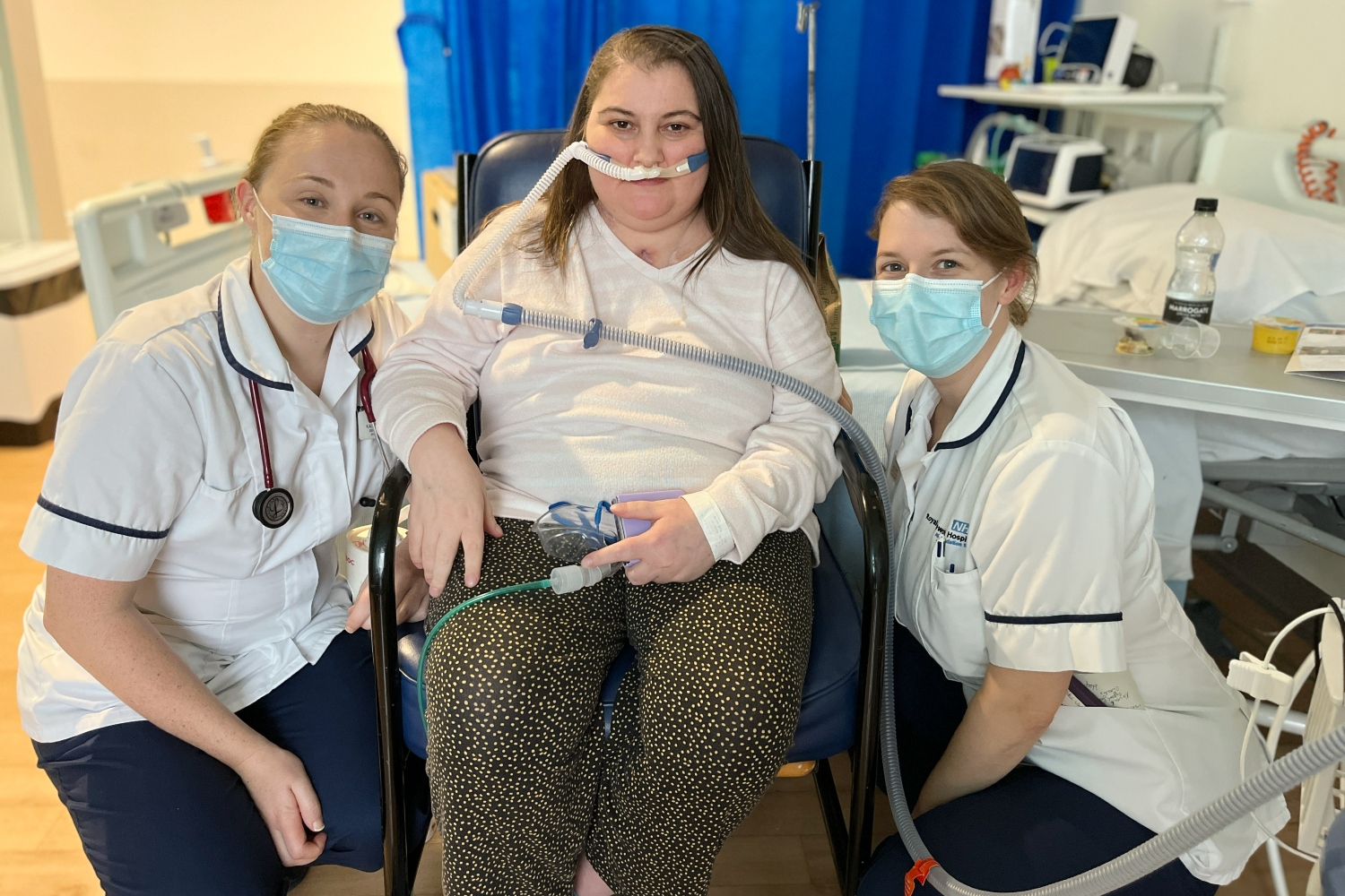 Two physios crouching next to Nicole in a wheelchair.