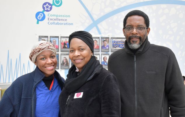 Transplant patient Progress stands smiling with her husband and daughter