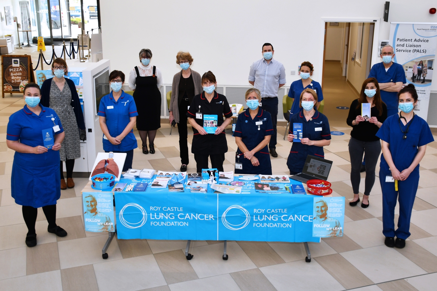 A group of people standing inside a hospital wearing masks.