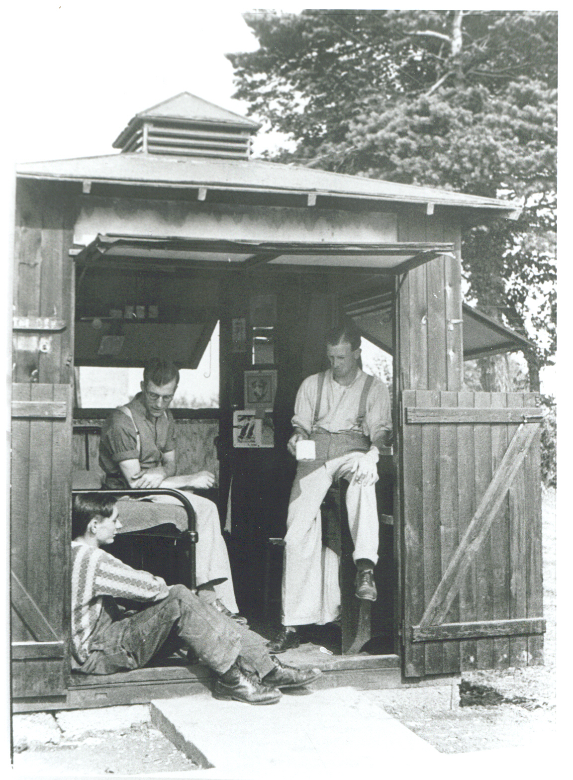 Men sitting in a shed with open windows.