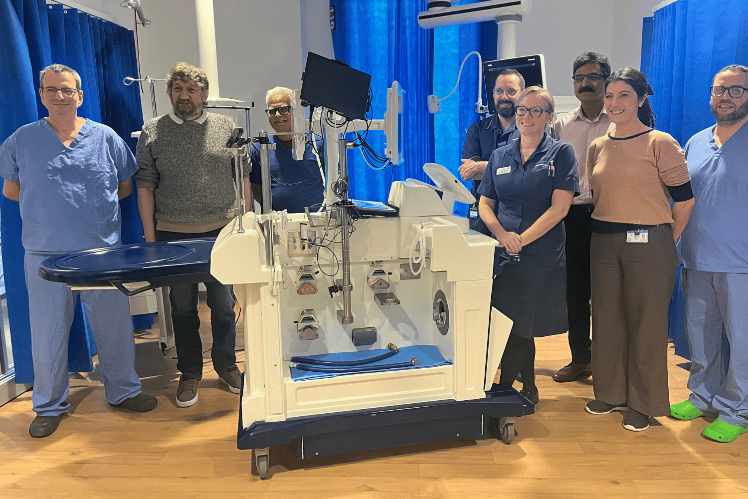 Eight people standing around a white machine with pipes and wires