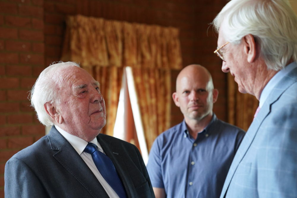 Two men in suits chatting to each other.