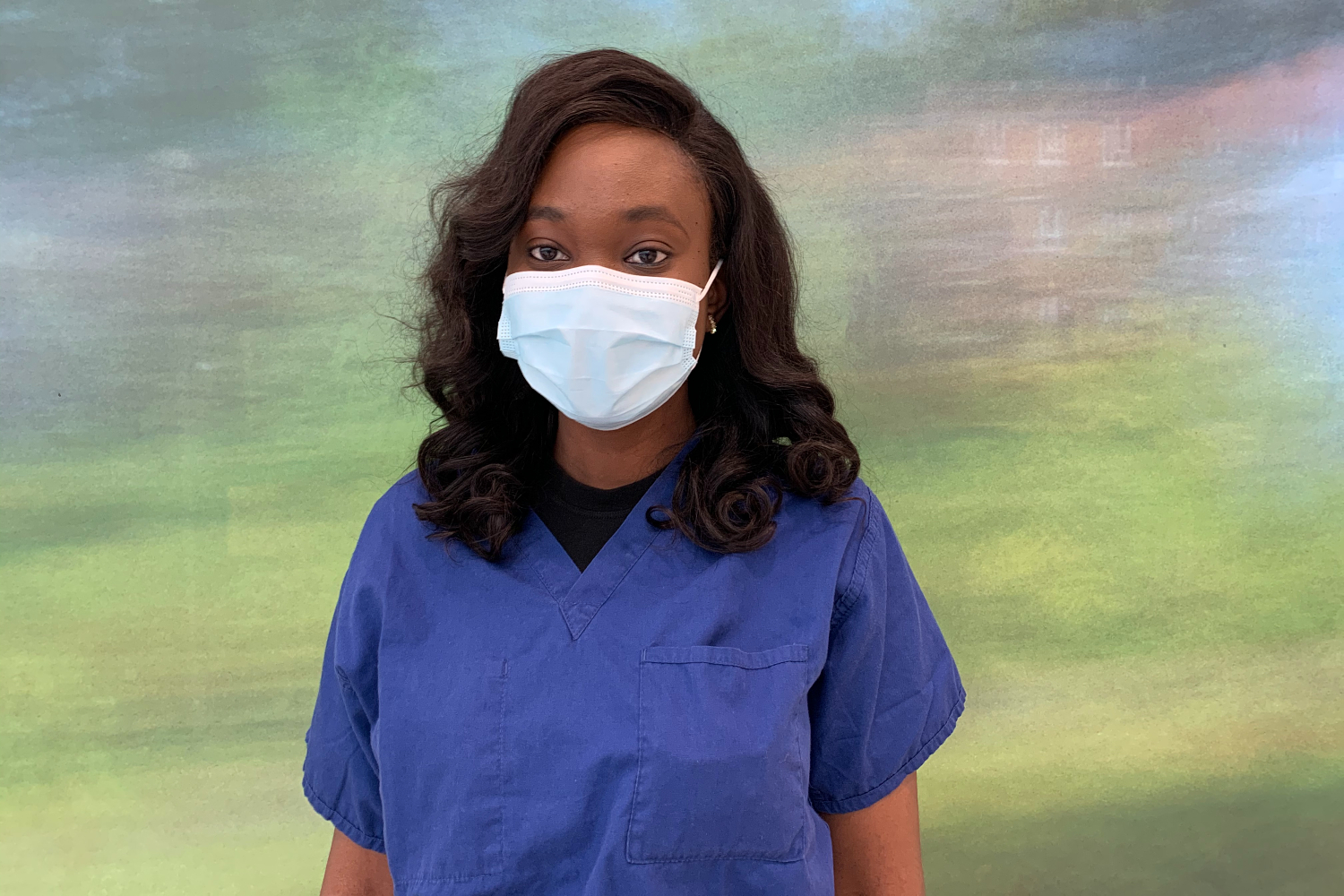 A woman in blue scrubs wearing a mask.