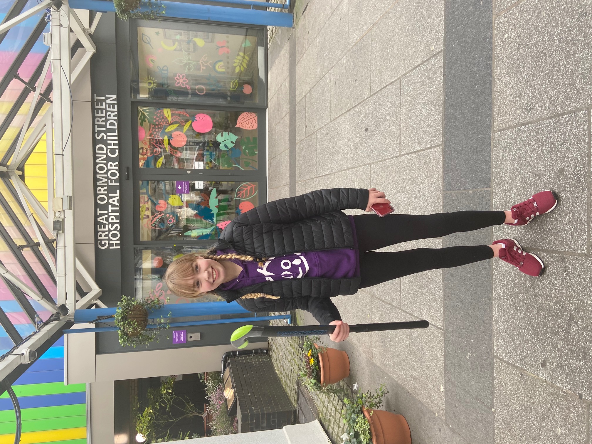 A girl stands with a hockey stick