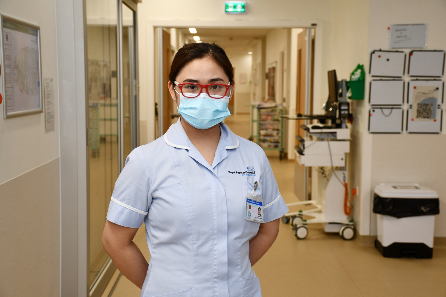 Nurse with red glasses stands in a corridor