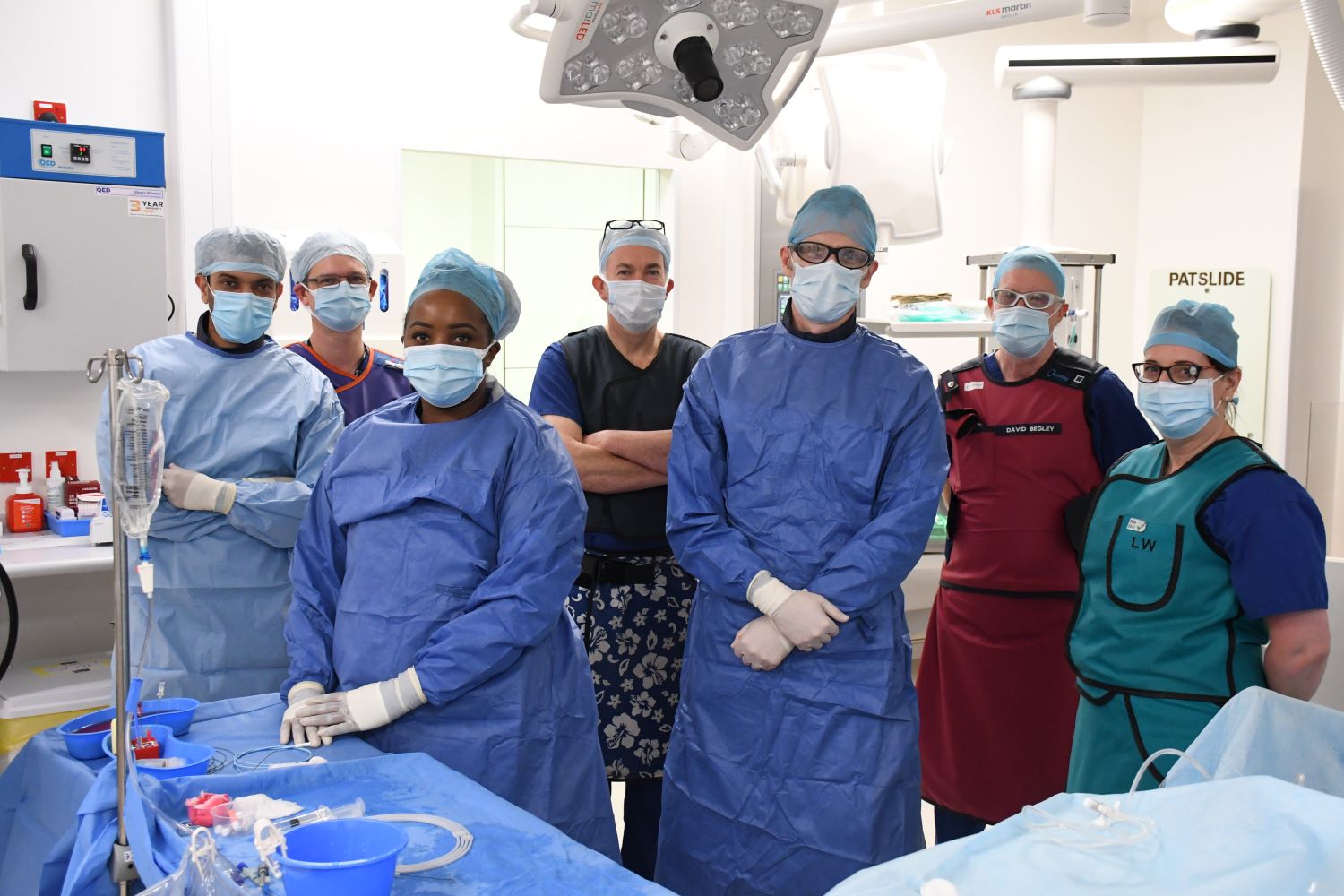 Seven people dressed in theatre scrubs and face masks