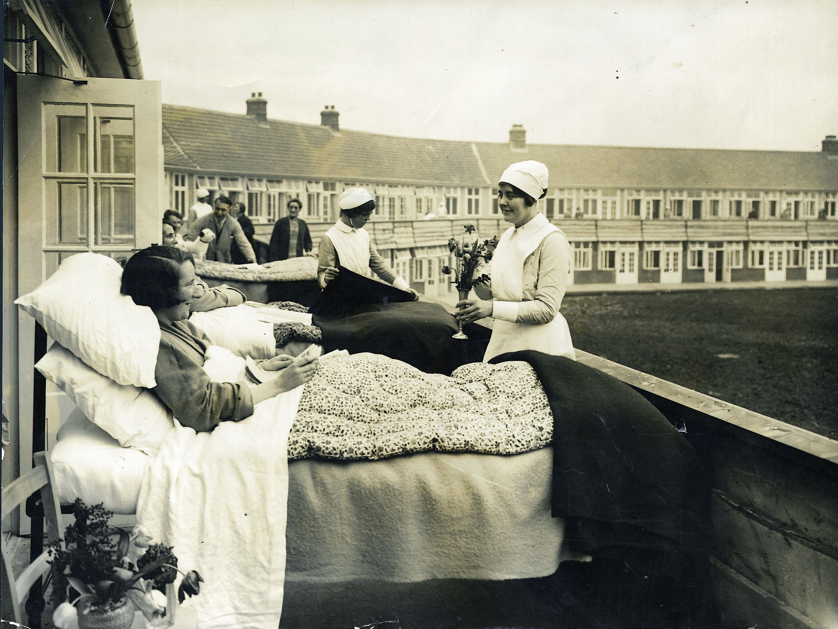An archive photo of women patients in beds on a balcony.