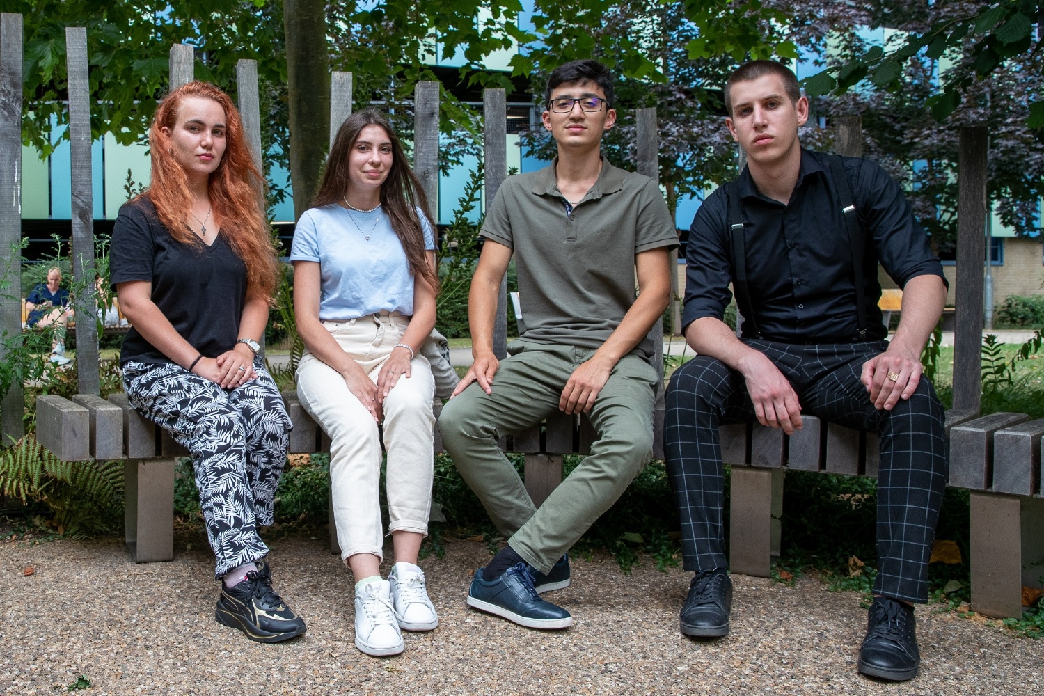 Four people sitting on a bench outside.