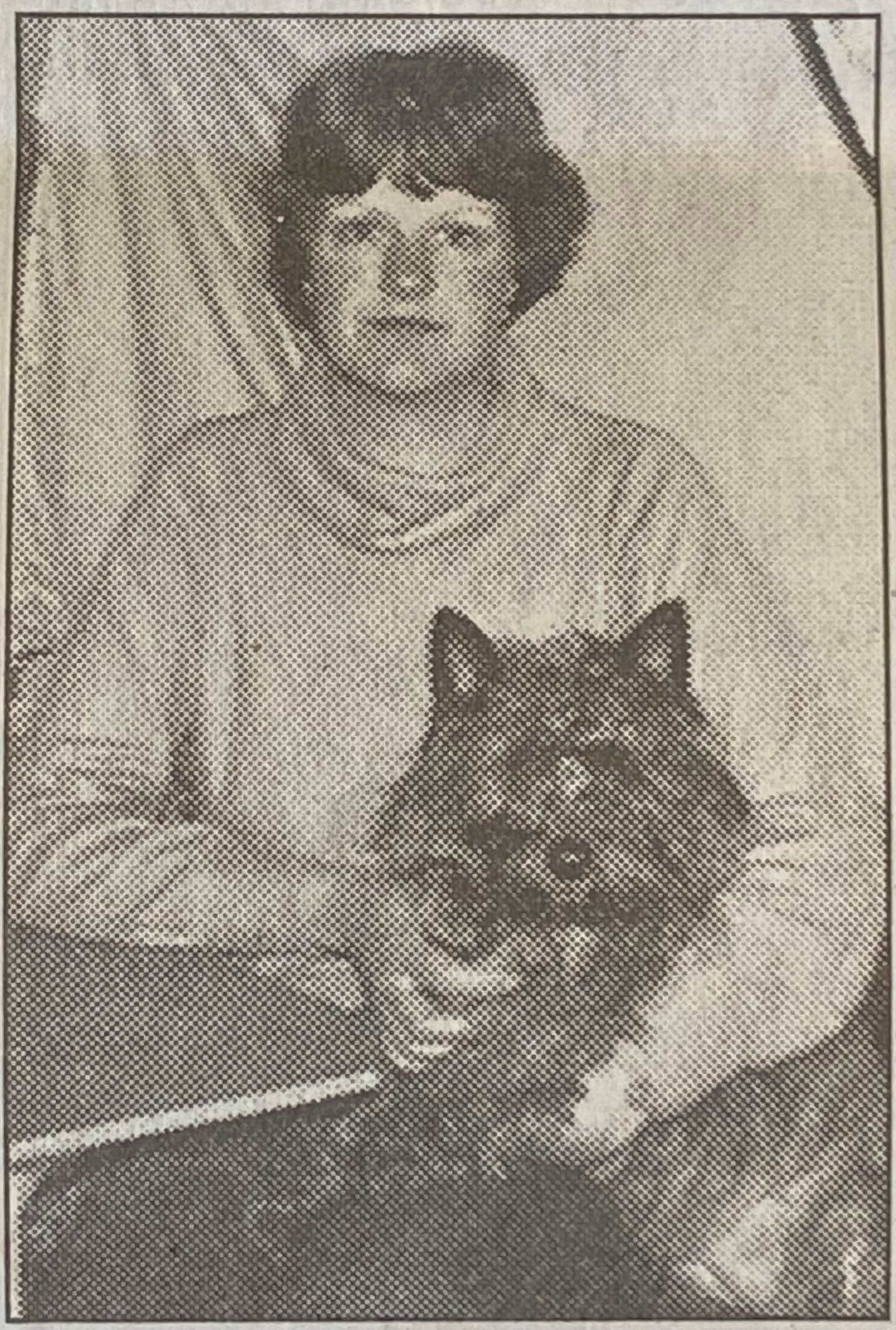 A black and white photo of Sandy as a teenager, sitting with a dog on her lap.