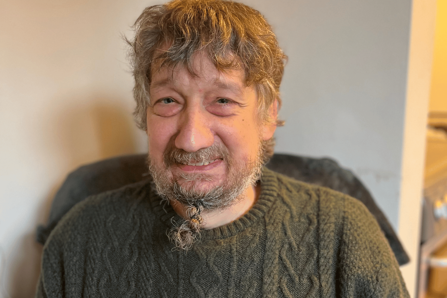 Daniel in a green jumper, smiling. 