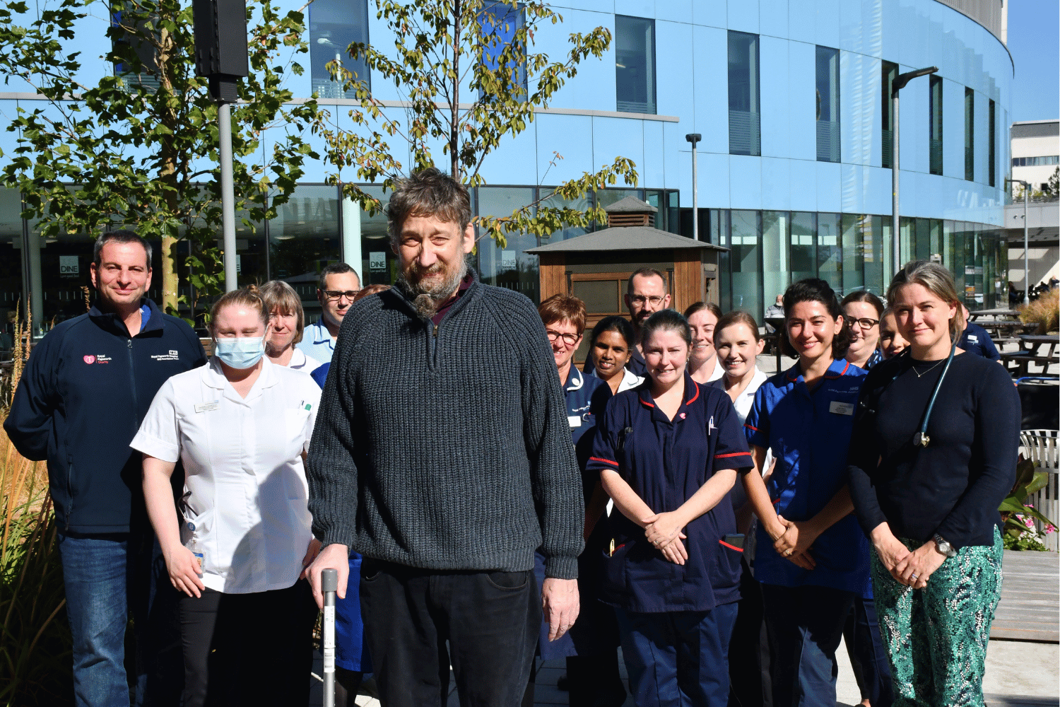 Daniel standing outside with 14 NHS staff who were caring for him.png